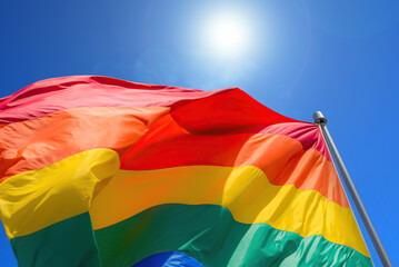 Rainbow flag on blue sky background symbol of tolerance and acceptance