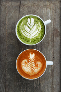 A cup of green tea matcha latte and cup of latte art coffee on wooden background                                                              