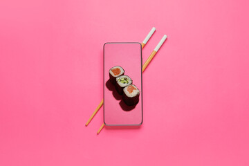 Tasty sushi rolls on screen of mobile phone and chopsticks on color background