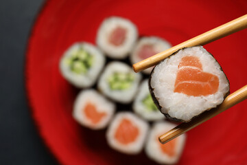 Chopsticks with tasty sushi roll, top view