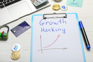 Laptop, credit card, money and clipboard with text GROWTH HACKING on white background
