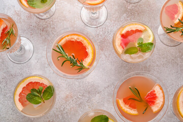 Glasses of tasty grapefruit cocktail on grey background