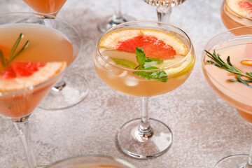 Glasses of tasty grapefruit cocktail on grey background, closeup