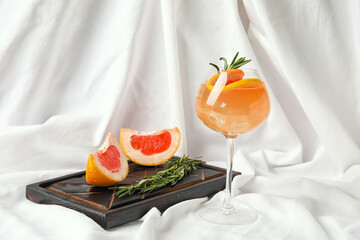Composition with glass of tasty grapefruit cocktail on fabric background