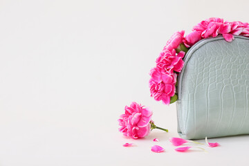 Bag with beautiful carnation flowers on color background