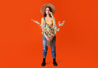 Beautiful young woman with blooming spring branches on color background