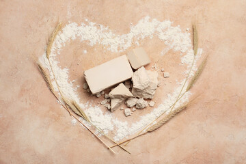 Heart made of flour with fresh yeast on color background