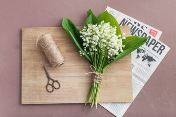Beautiful lily-of-the-valley flowers, scissors and rope on color background