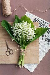 Beautiful lily-of-the-valley flowers, scissors and rope on color background