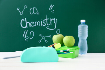 Pencil case and stationery near blackboard with word CHEMISTRY © Pixel-Shot