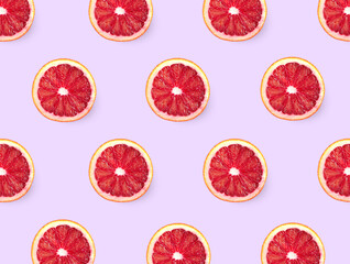 Slices of red oranges on pink background, flat lay