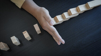 Businesswoman stops hands falling over domino to stop risk continuously, Continuous damage...