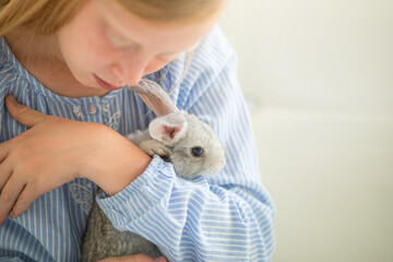 red-haired girl plays with a rabbit in a light interior, tenderness with an animal