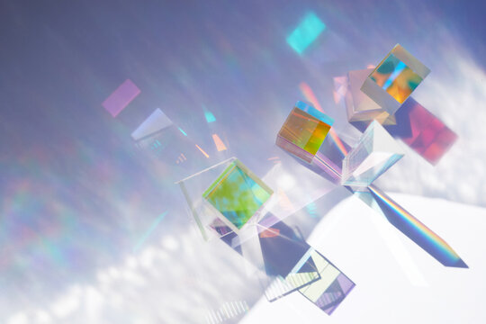 Abstract background with glass geometric figures prisms with light diffraction of spectrum colors and complex reflection.