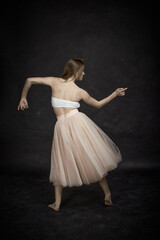 Fototapeta na wymiar Young girl in white top and peach skirt dancing