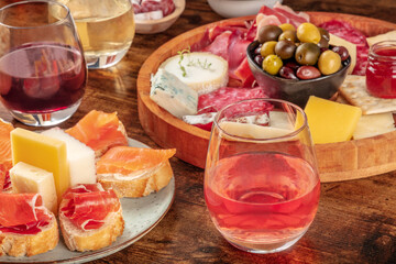 Wine, sandwiches, charcuterie and cheese board on a rustic wooden background. Spanish tapas or Italian antipasti on a table in a bar. Gourmet appetizers