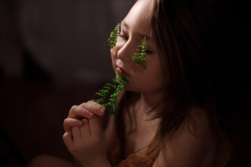 Ecology concept, little girl with fern sprigs pasted with plasters on her cheeks holding twig