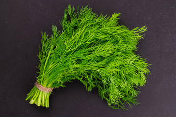 A bunch of dill on a black background. Flat lei. Close-up.