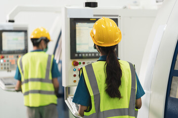 Back of Asian female worker in yellow helmet work at machine control panel in factory production line with copy space.
