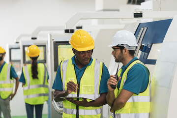 Caucasian and African worker discuss together in factory production line machine. Concept of multi ethnic group of people and diversity with copy space.