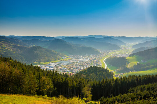 Germany, Aerial drone view above endless valley surrounded by green tree covered mountains and houses of city hausach im kinzigtal
