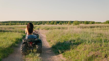 The girl drives an Quad Cycle, adventure, travel, tourism. Free woman ride a Quad bike in park in summer on a dirt road. Off-road ATV adventure. Outdoor activities in summer in spring, travel outdoors