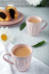 Two cups of freshly made coffee with cream with cupcake and chamomile flowers