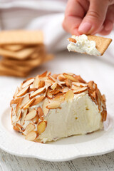 Woman's hand holding cracker with cheese snack. Homemade classic cheese ball.