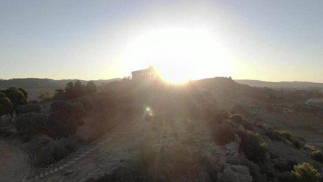 Gold sunrise aerial of Roman Temple of Juno in Sicily with lens flare