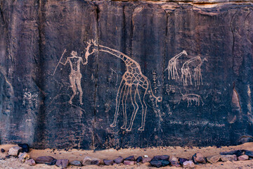 Neolithic rock art. Prehistoric rock engraving  depicting a human and a giraffe. Wilaya Tamanrasset, Hoggar Mountains,Tassili nAjjer National Park, South Algeria, Africa, - obrazy, fototapety, plakaty