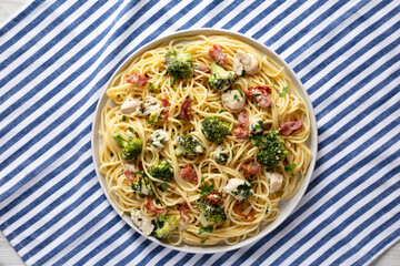 Homemade Chicken Bacon Broccoli Alfredo on a plate on a white wooden background, top view. Flat lay, overhead, from above.