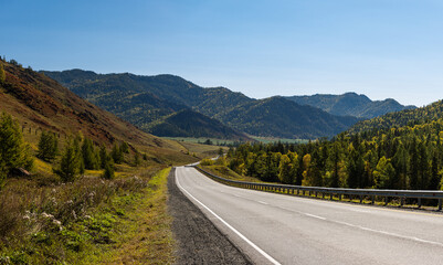 Fototapeta premium Beautiful landscape. The road that goes into the distance, mountains on the horizon, forest and hills