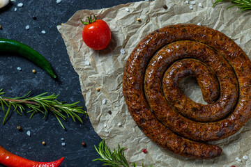 Snail sausage baked in an old oven is on dark background