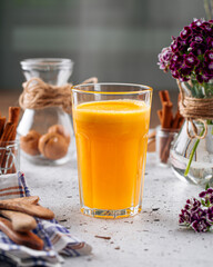Side view on glass of fresh orange juice on a light background