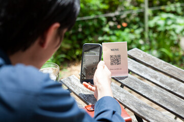 カフェでQRコードをスマートフォンで読み取る男性