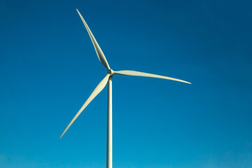 Windmill turbine propeller against blue sky. Natural green energy conservation concept