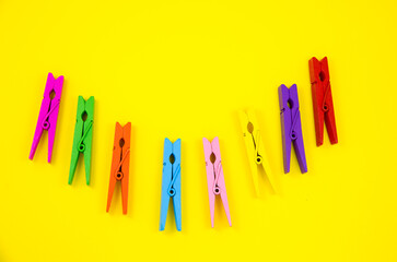 Colorful wooden clothespins on yellow background. Close up, copy space. Minimalism, original and...