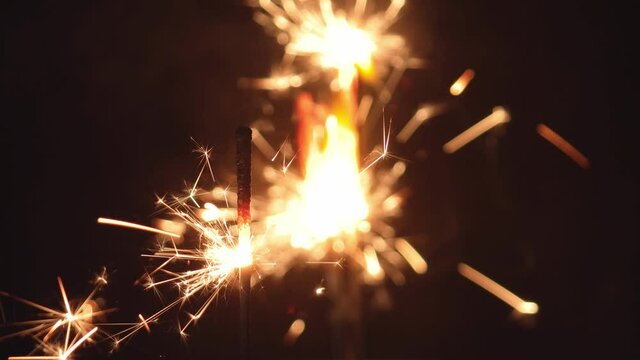 Firework sparkler burning at night in front of black background.