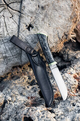 Handmade hunting knife among the stones in nature. Photo outside of a sharp homemade knife. A man's gift. Blade. Fishing. Picnic. Rest in the wild.