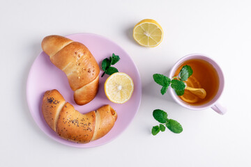 Close-up top view of green tea with lemon and mint in a glass cup. Tea party with rich bagels. Selective focus.