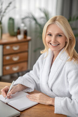 Good-looking cute woman in white sitting at the table