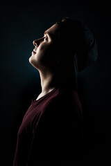 Portrait of a young man in a cap looking up, in profile on a black background