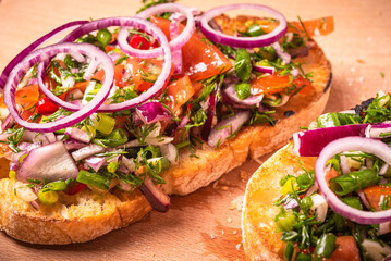 Vegetarian bruschetta with chopped vegetables and olive oil on a wooden board, macro, close-up, rustic style. Italian appetizer