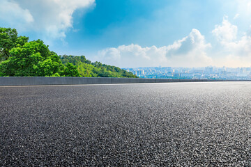 Asphalt road and city skyline with mountain landscape.