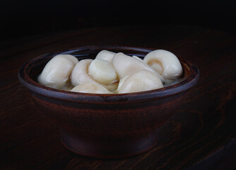 Clay plate with marinated champignons. Champignon mushrooms.