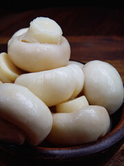 Small pickled champignons in a clay plate. Pickled champignons mushrooms.