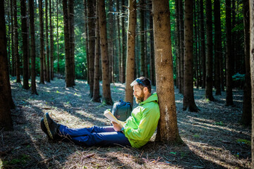 man reading a book in forest
