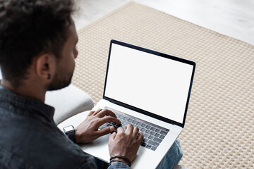 Young man working at home, Mixed race student using laptop computer with empty white blank screen mock-up, meeting online, web conference, studying, e-learning, technology concept - Powered by Adobe