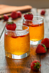Homemade lemonade with strawberries. Nice cold drink. Summer drink with berries. A pair of glasses of kombucha with additional flavors on wooden table