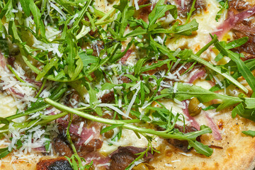 Delicious Italian wood-fired pizza with creamy sauce, oyster mushrooms, capers, arugula and truffle on a gray background. Hard light.